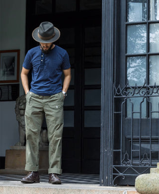 Olive bermuda pants worn with cuffed hem, button fly, and front pockets