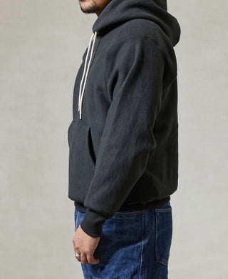 Black pullover hoodie with kangaroo pocket and long sleeves, side profile