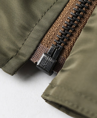 Jacket zipper close-up with brown leather pull tab and dark teeth