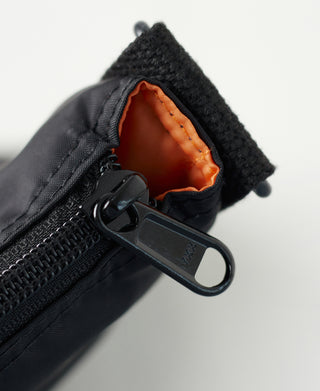 Black nylon helmet bag zipper opening with orange lining and metal zipper pull