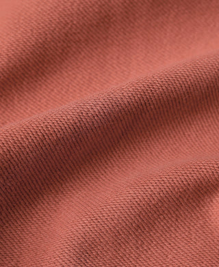 Brick red terry cloth full-zip hoodie fabric close-up, textured knit on folds