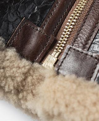 Close-up of zipper pull tab and stitching on dark brown flight jacket with shearling edge