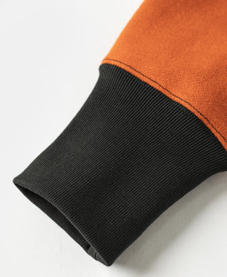Orange sleeve end with ribbed dark cuff on two-tone sweatshirt.