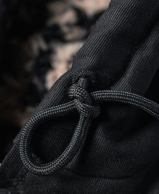 Black drawstring with cord stopper detail near the jacket hood