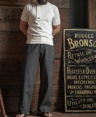 White henley T-shirt worn with gray trousers, short sleeves and button placket
