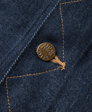 Indigo denim jacket pocket rivet close-up with N&S brass logo button.