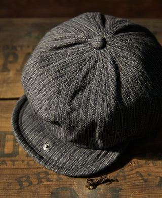 Black and gray yarn-dyed newsboy cap with side buttons and curved brim.