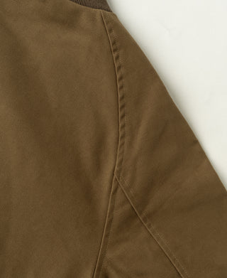 Brown bomber jacket side panel with diagonal seam stitching and reinforced edge.