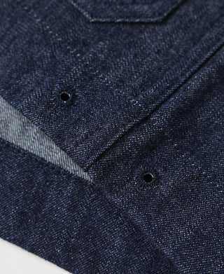 Indigo denim utility coverall jacket button placket and pocket corner close-up