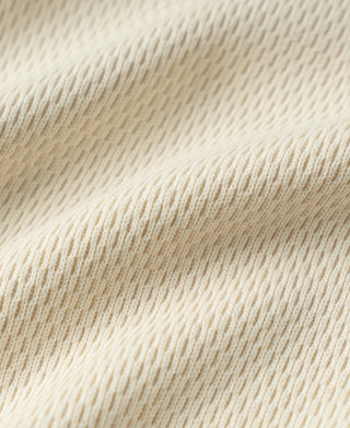Thermal waffle-knit shirt fabric texture close-up in light apricot/cream