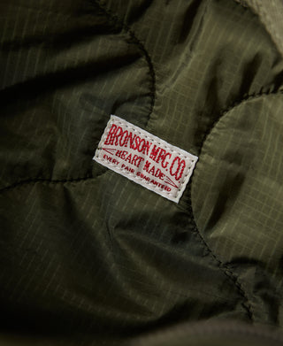 Close-up brand label on olive padded fabric panel of waist bag