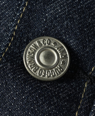 Indigo denim jacket metal snap button with embossed branding and yellow stitching.
