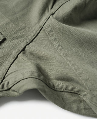 Olive fatigue jacket sleeve with curved seam and stitched hem edge