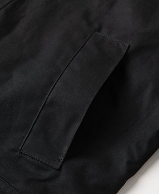 Black waxed jacket sleeve or side panel close-up with reinforced rectangular seam