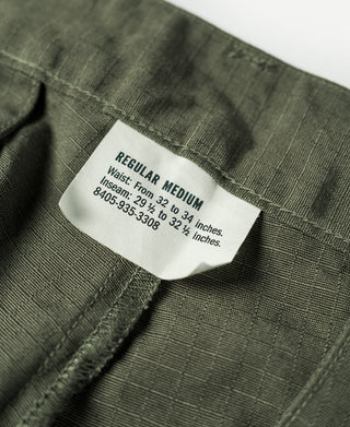 Olive fatigue pants label at waistband with size and care text