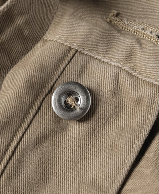 Khaki bermuda shorts fabric close-up with round metal button and stitched edge