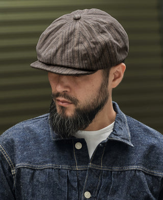 Dark gray striped newsboy cap worn by a man, side profile