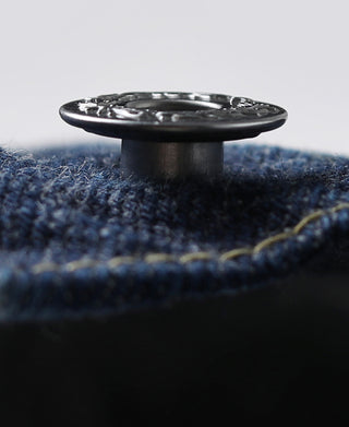 Indigo denim jacket button close-up with yellow stitching