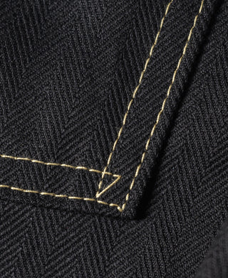 Black jacket hem corner with gold topstitching and stitched reinforcement seam