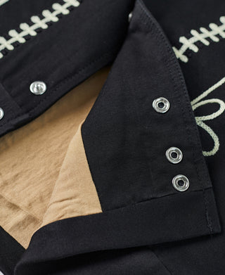 Black jacket sleeve with cream cross-stitch trim and snap buttons on cuff