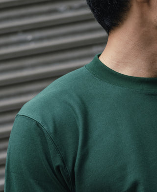 Green T-shirt crew neckline and shoulder seam detail, smooth knit fabric.