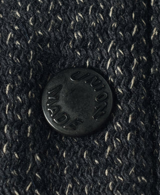 Round dark button on dark salt-and-pepper wool vest