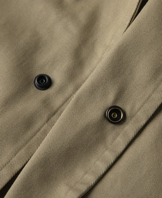 Khaki trench coat front close-up with dark button snaps on flap