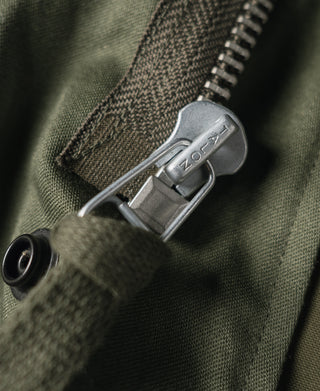 Olive field jacket zipper with metal pull and riveted stitching detail