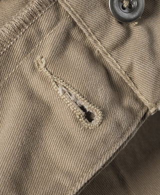 Khaki military trousers fabric with stitched pocket edge detail, showing wear marks