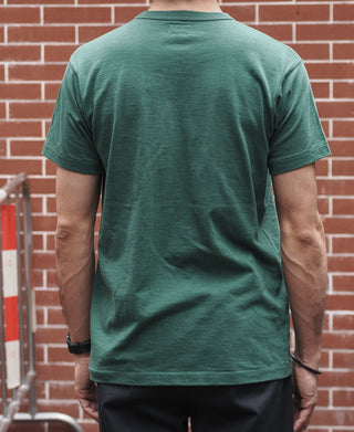 Back view of green crew-neck pocket T-shirt on model