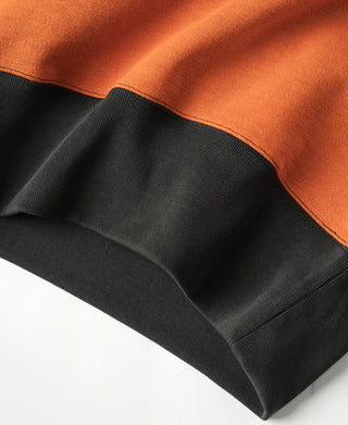 Dark ribbed hem with orange upper panel on two-tone sweatshirt.