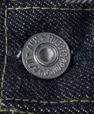 Indigo denim close-up of branded metal rivet button at waistband