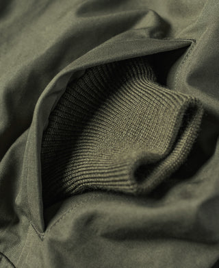 Olive jacket fabric with ribbed knit cuff texture, close-up