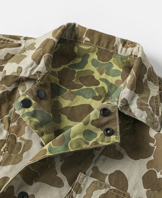 Camo hooded jacket close-up with front snaps and flap collar.