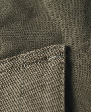 Olive vest fabric close-up with rugged stitched seam