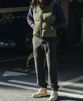 Olive quilted padded vest worn over dark long sleeves with casual pants