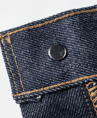 Dark blue denim jeans patch pocket corner with small metal button and contrast stitching