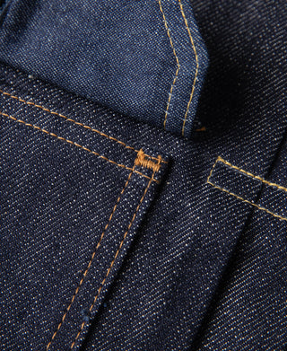Indigo denim jacket seam detail with orange stitching and small bar tack