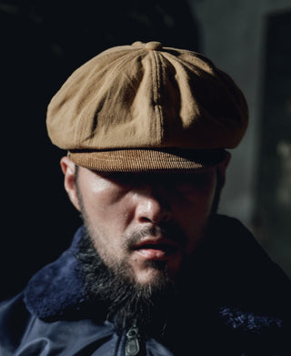Khaki biker cap worn by a man with short beard.
