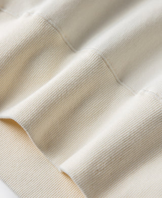 White raglan sweatshirt with ribbed cuffs and hem, smooth knit fabric close-up.