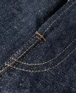 Dark blue denim jeans close-up of arcuate pocket stitching with contrast thread.