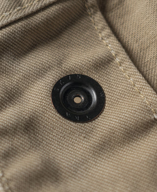 Khaki combat pants close-up of black fabric button on pocket flap