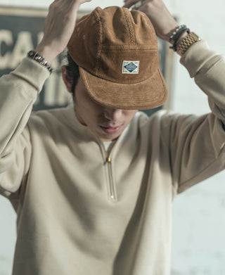 Khaki corduroy 5-panel cap on a model’s head, with front logo patch