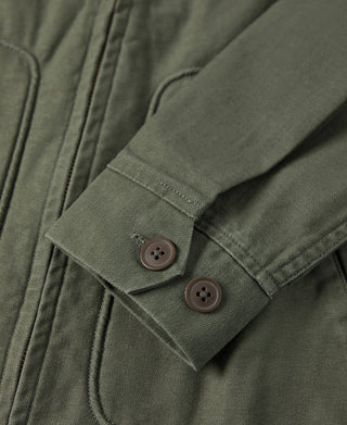 Olive jacket cuff with two dark buttons and stitched sleeve placket