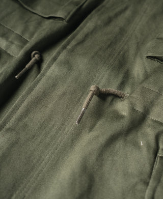 Olive field jacket front with drawstring cord and buttoned flap, close-up