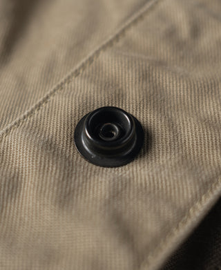 Khaki combat pants close-up of black round button on fly area