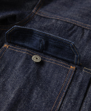 Indigo denim jacket pocket flap with round metal button and orange topstitching
