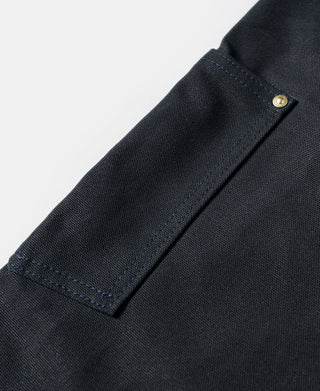 Navy canvas pants hem detail with folded cuff edge and small brass button