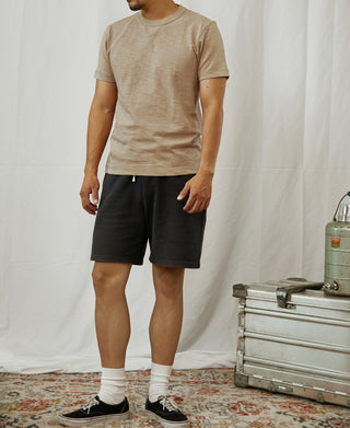 Light tan crewneck cotton T-shirt worn with dark shorts