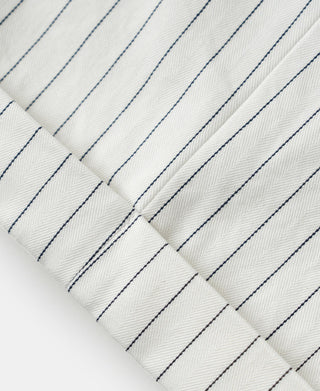 White pinstripe work pants fabric with thin blue stripes and stitched seams
